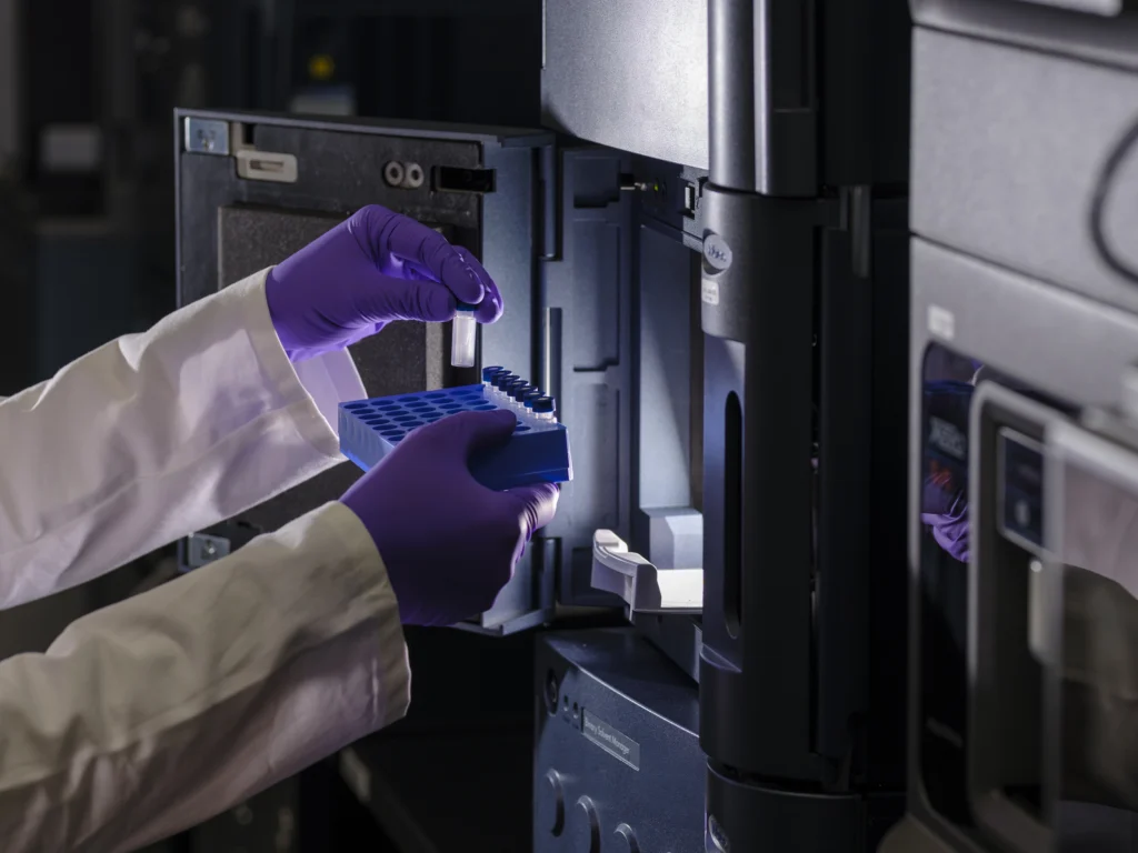 Mains gantées en train d'installer des échantillons dans une machine de chromatographie